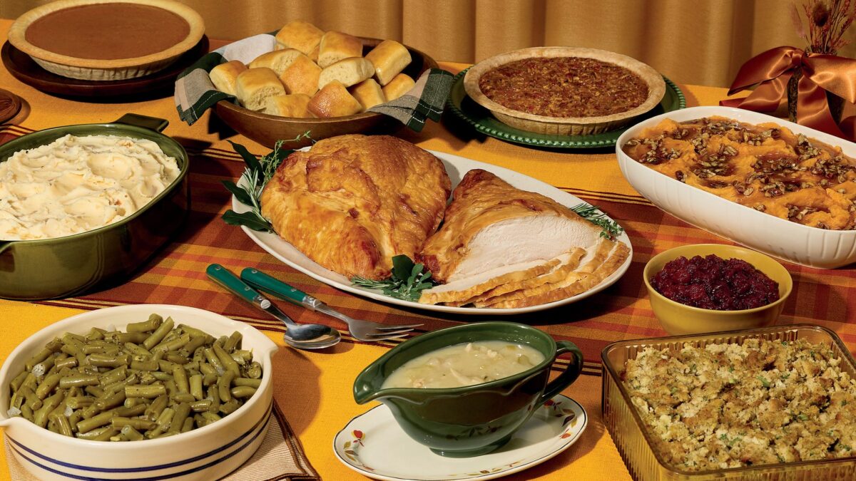 Cracker Barrel Turkey Feast with sliced turkey breast, sides, rolls and pies on a table